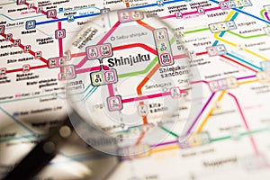 Shinjuku Tokyo metro station on a printed paris metro map under a magnifier lens