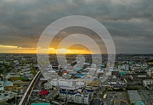 Shinkansen rolls through small town at sunset as storm clouds gather overhead