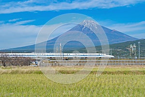 Shinkansen train. Fast bullet train, driving and passing Mountain Fuji near Tokyo railway station with with green rice field,