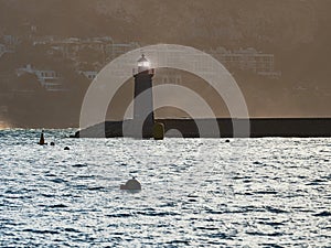 Shinning lighthouse at the end of pier, shaking buoy