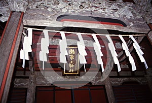 Shinto prayer papers hang from roof of shrine.