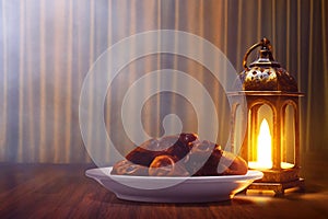 Shiny arabic lantern and bowl of fresh dried dates on wooden floor with gold curtain at night