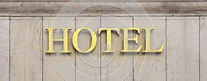 Shiny brass Hotel sign on stone wall building facade