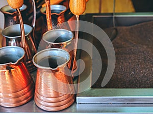 Shiny bronze-colored metal turks stand next to sand to make oriental coffee photo