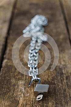 shiny chain with padlock unlocked on a wooden table