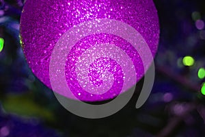 Shiny Christmas ball, on a blurred background of a green Christmas tree, part of the ball in the frame, open frame, close-up