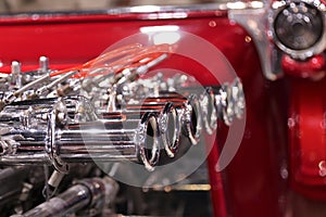 Shiny chrome exhaust on red hot rod engine