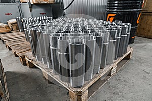 Shiny circular precision stainless steel industrial machine parts arranged in rows on pallet. Steel products to