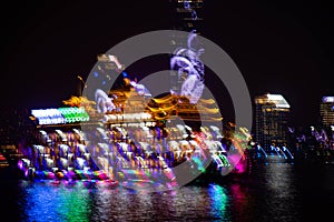 Blurry neon lights of night cityscape and ship at river in Shanghai China. Intentional motion blur