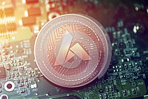 Shiny copper ARDOR cryptocurrency coin on blurry motherboard background photo