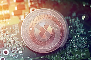 Shiny copper AXT cryptocurrency coin on blurry motherboard background