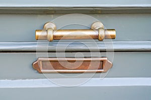 Shiny copper mailbox door handle metal postbox on green blue old-fashioned wooden door in classic design close-up