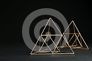 Shiny decorative gold pyramids on black background