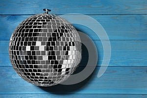 Shiny disco ball on blue wooden background, top view. Space for text