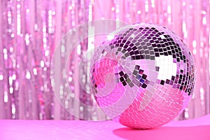 Shiny disco ball on blurred background, toned in pink. Space for text