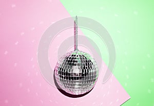 Shiny disco ball on a bright pastel creative background. Pop disco music style attributes eighties