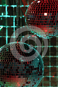 Shiny disco balls against foil party curtain under color lights