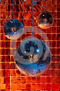 Shiny disco balls against foil party curtain under color lights