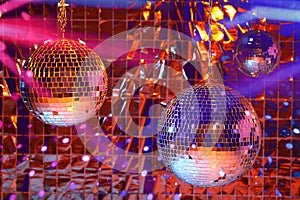 Shiny disco balls against foil party curtain under light