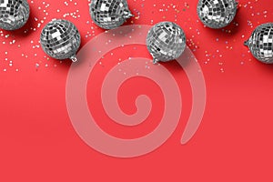 Shiny disco balls and confetti on red background, flat lay. Space for text