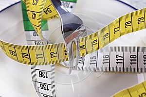 A shiny fork crushes a multi-colored centimeter in a white plate with a blue border