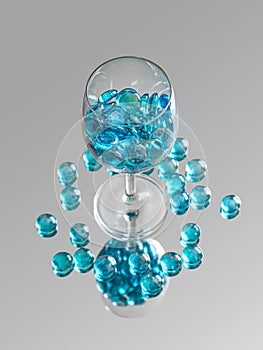 Shiny glass stones, bright turquoise color, in a glass on a thin leg