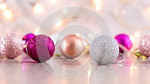 Shiny glitter pink gold and silver Christmas ornaments and blinking lights behind