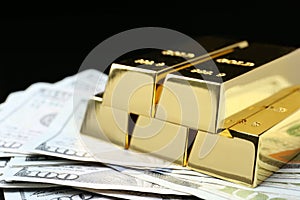 Shiny gold bars and money on black background