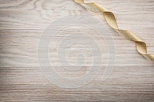 Shiny gold ribbon in top right corner on wooden background