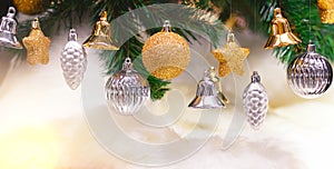 Shiny gold and silver christmas balls, stars and bells on white with pine tree for new year