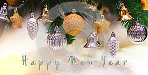Shiny gold and silver christmas balls, stars and bells on white with pine tree for new year with happy new year text