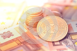 Shiny golden AXT cryptocurrency coin on blurry background with euro money