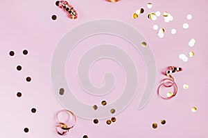 Shiny golden confeti and ribbons on pink background. photo
