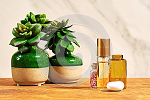 Shiny golden perfume bottle with a small flask with pink petals and succulents