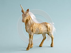 Shiny golden unicorn on a pastel blue background. Minimal art fantasy poster