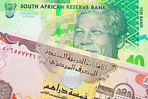 A shiny, green 10 rand bill from South Africa paired with a colorful five dinar bank note from the United Arab Emirates.