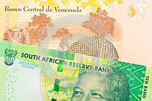 A shiny, green 10 rand bill from South Africa paired with a colorful, yellow five Bolivar bank note from Venezuela.