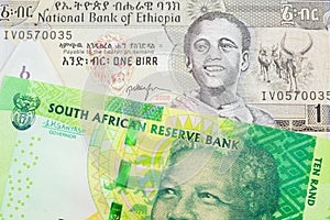 A shiny, green 10 rand bill from South Africa paired with a grey Ethiopian one birr bill.