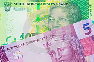 A shiny, green 10 rand bill from South Africa paired with a pink and purple five real bank note from Brazil.