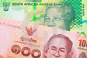 A shiny, green 10 rand bill from South Africa paired with a red, one hundred baht note from Thailand.