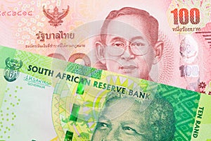 A shiny, green 10 rand bill from South Africa paired with a red, one hundred baht note from Thailand.