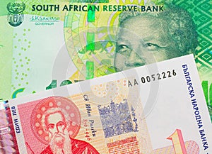 A shiny, green 10 rand bill from South Africa paired with a red and white one lev bank note from Bulgaria.