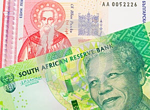 A shiny, green 10 rand bill from South Africa paired with a red and white one lev bank note from Bulgaria.