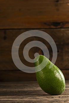 Shiny green avocado on wood