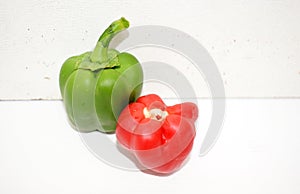 A shiny green bell pepper along with a fresh headless red bell pepper on a white background with their lighting and shadows