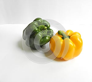 A shiny green bell pepper next to a fresh yellow bell pepper with different angles on a white background