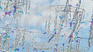 Shiny hanging butterfly decoration swaying in wind against cloudy blue sky