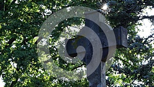 Shiny holy cross with sparkling sunbeams through foliage and sky shine a light of spiritual faith and christianity with symbol for