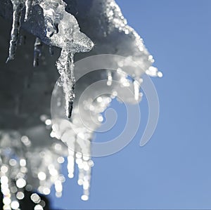 Shiny icicles melt and drip on the roof in the spring