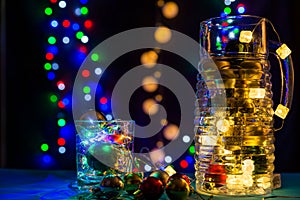 Shiny jug and glass are on the brightly table/background. Merry Christmas. Happy New Year.